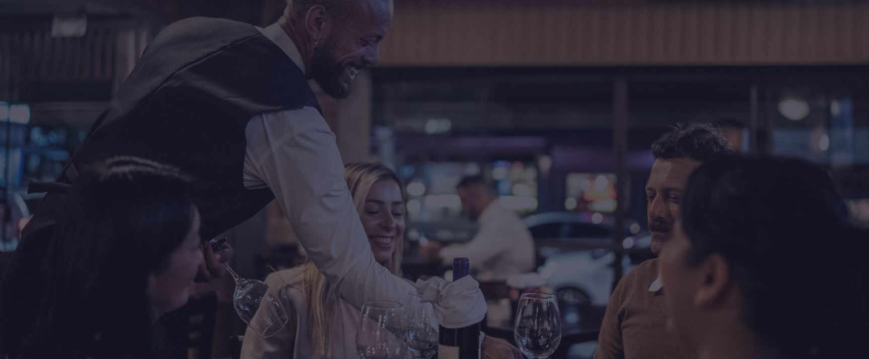 A sommelier presenting wine to guests at a restaurant table
